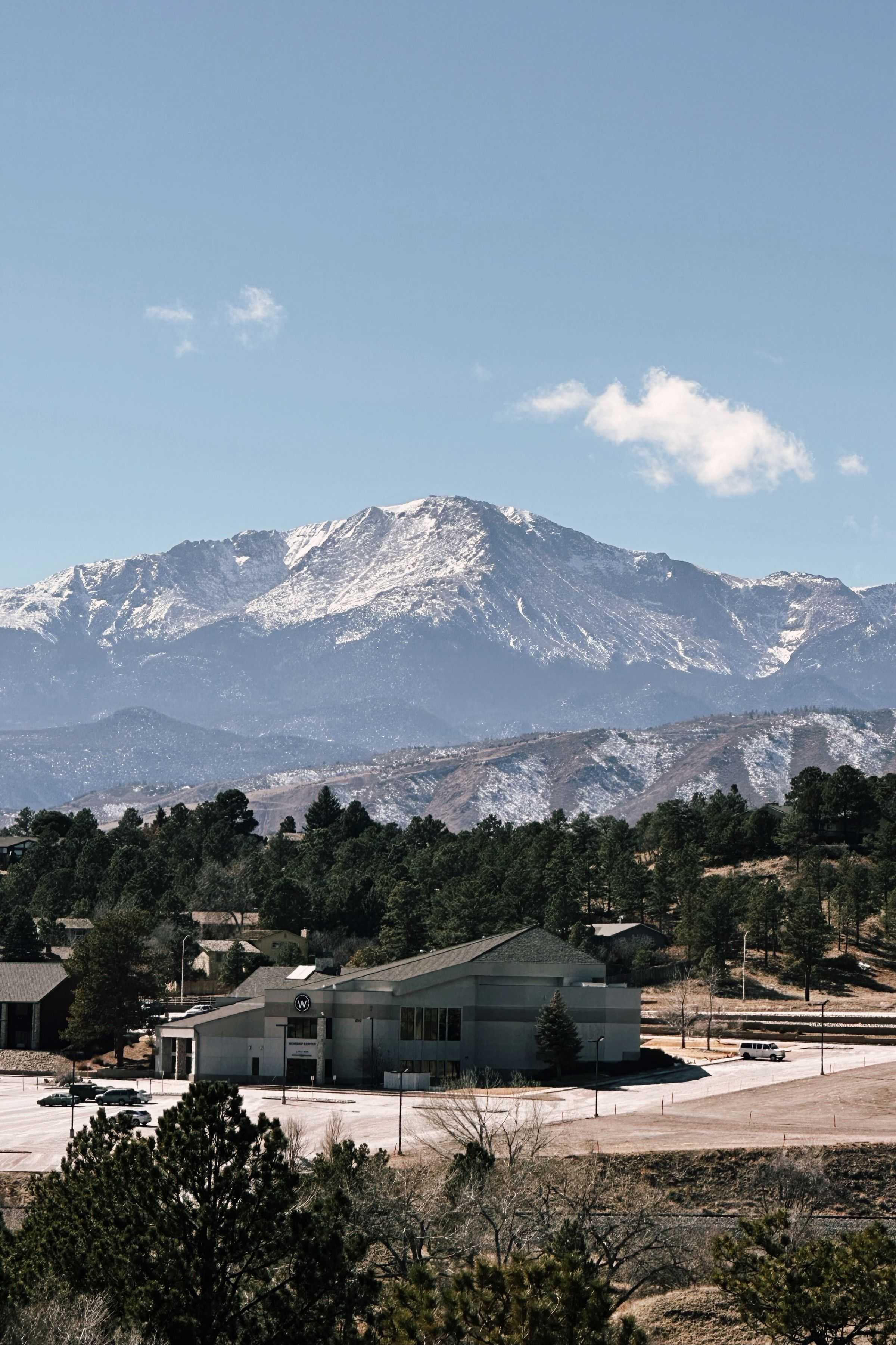 Snow-capped Colorado mountain above pine trees and neighborhood homes