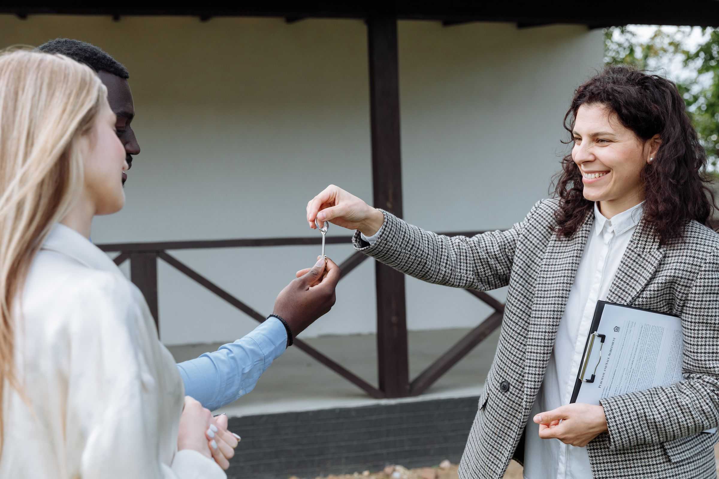 A real estate agent handing the keys to a couple at their new home